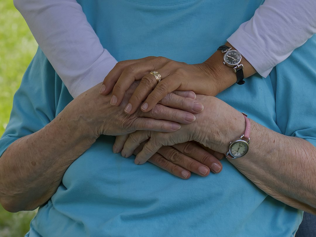 Caregiver holding the hands of an elderly person, representing compassionate home care