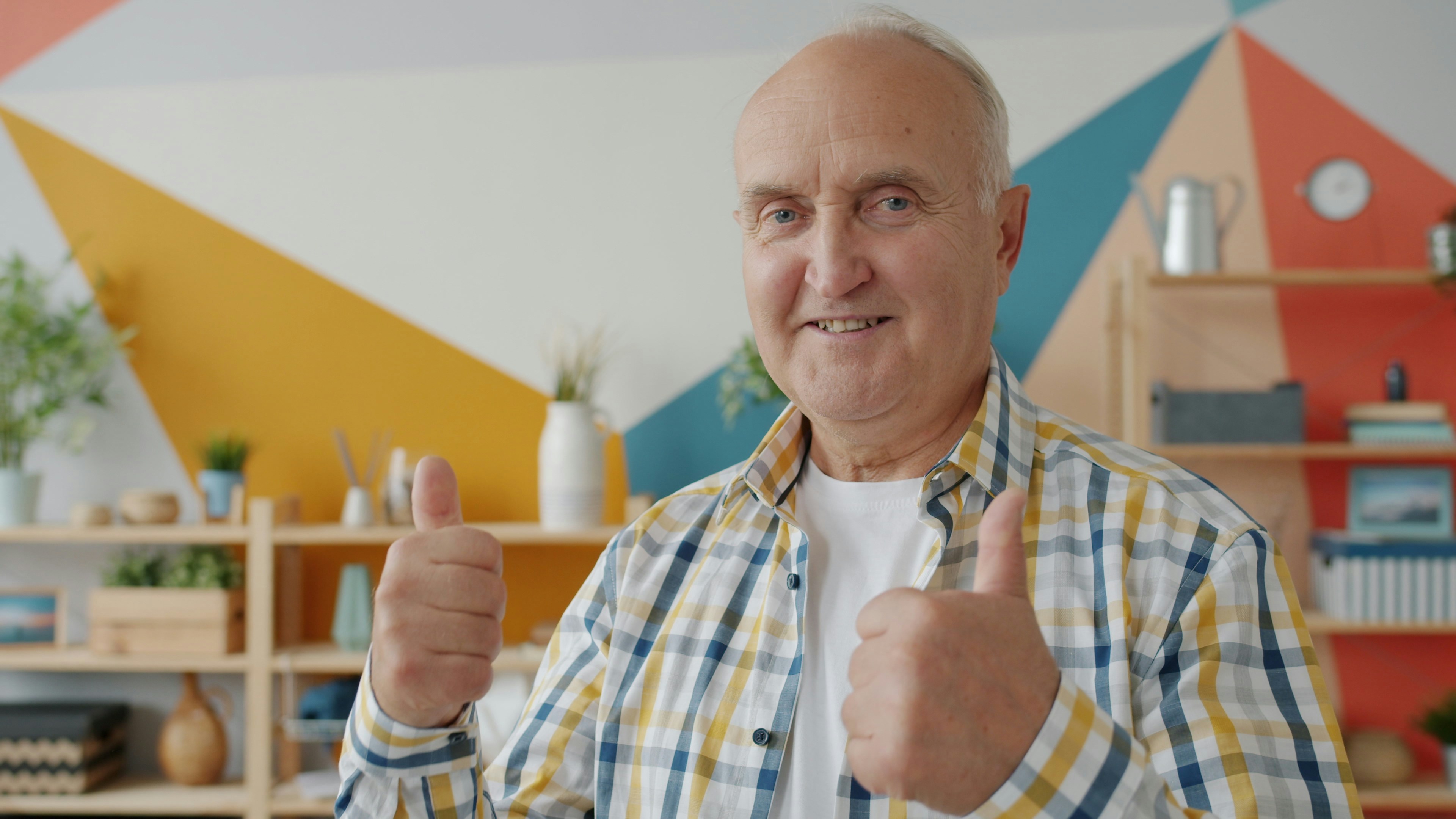Smiling senior man giving thumbs up at home, independent living