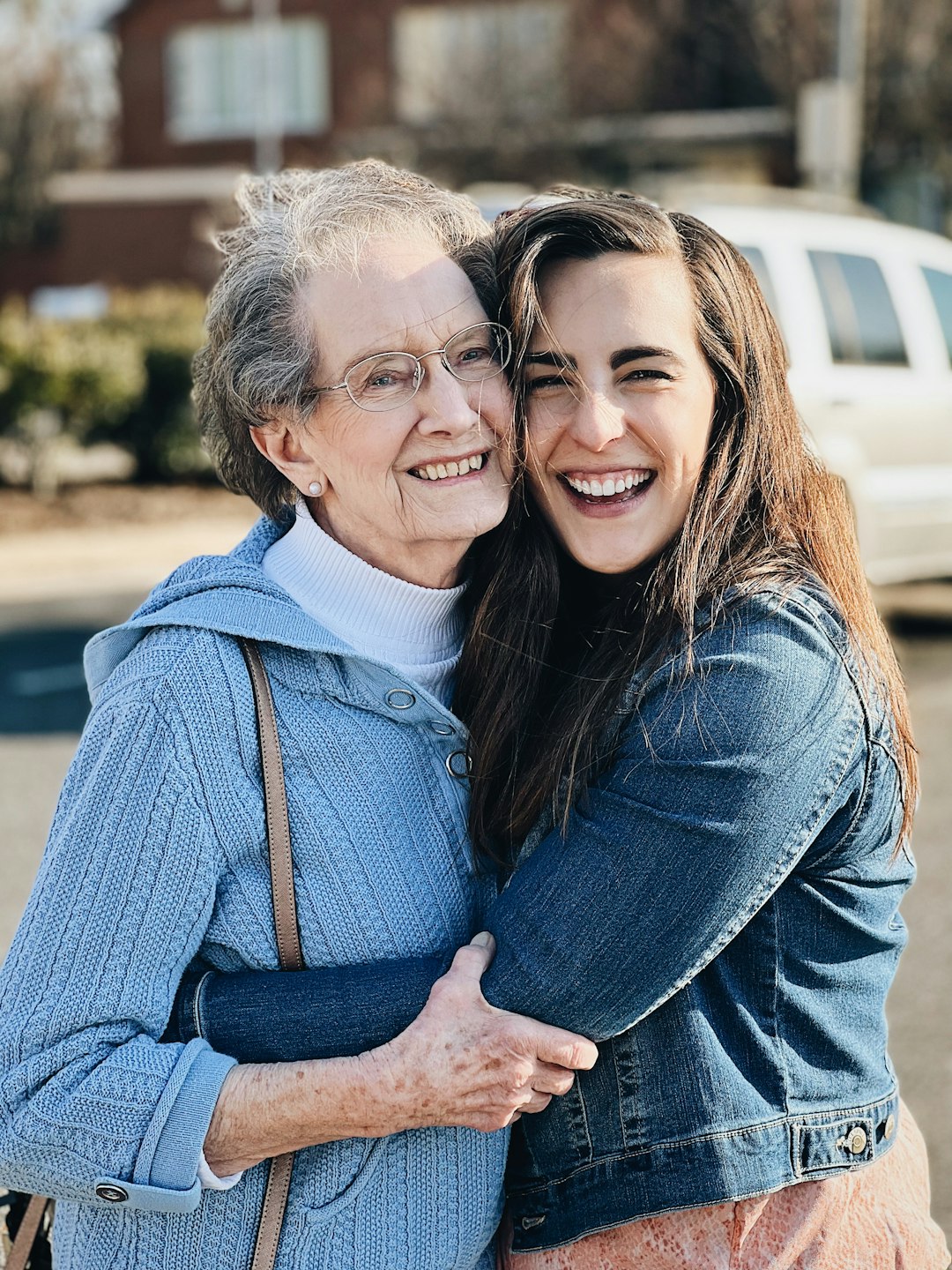Smiling elderly woman hugging her granddaughter, family caregiver support
